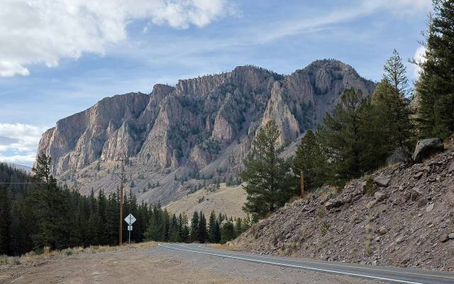 Highway 149 curving below tall cliffs of volcanic rock near Creede