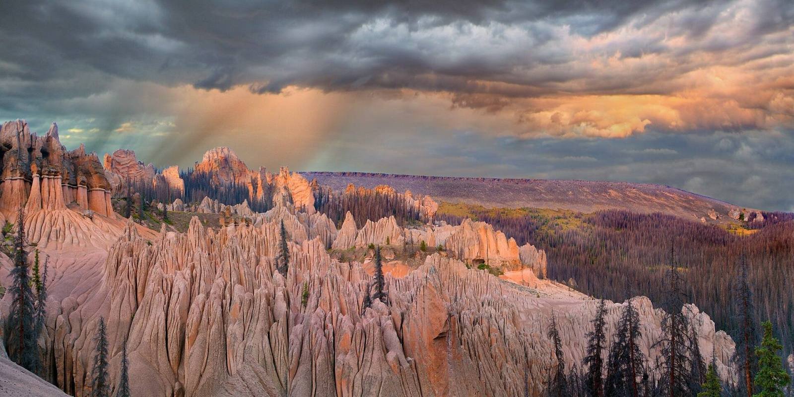 A wide view of the eroded spires of the Wheeler Geologic Area under a stormy sky