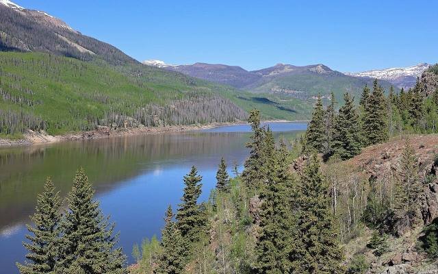 The blue water of the Rio Grande Reservoir between forested mountains