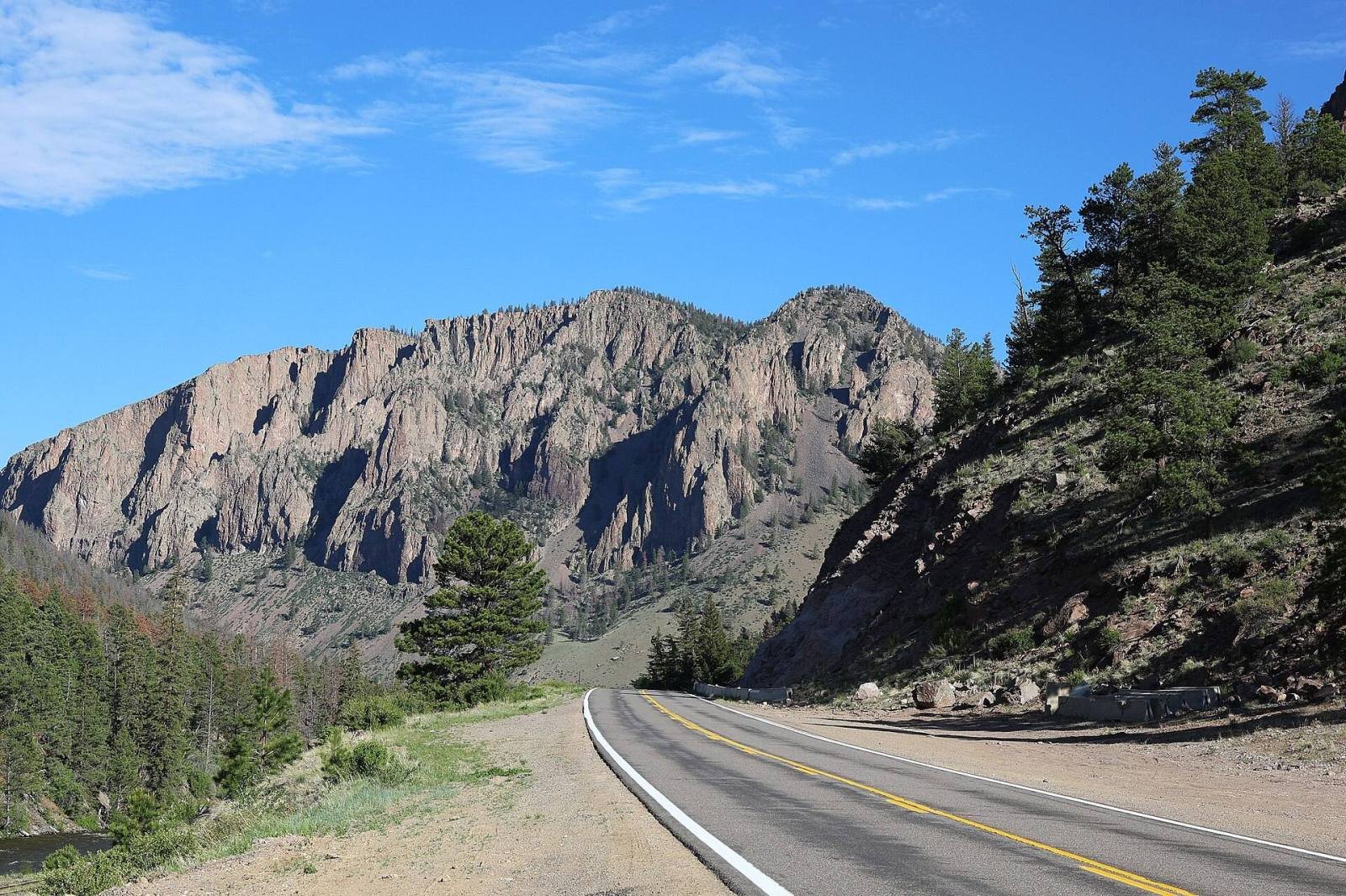 Highway 149 curving below a tall cliff of volcanic tuff near Creede