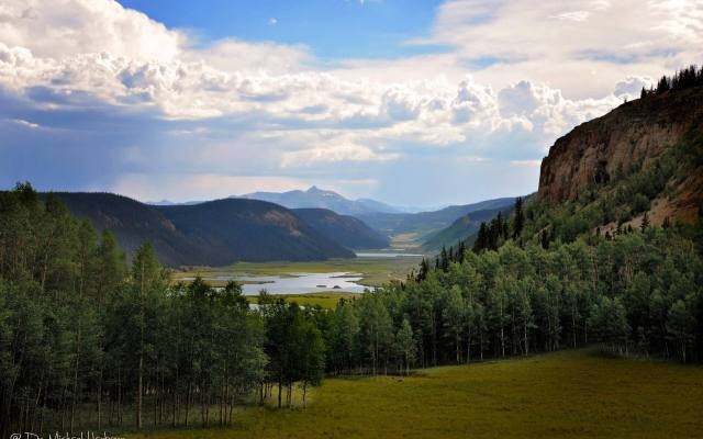The upper Rio Grande valley near Creede seen from a forested hillside under summer clouds