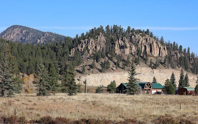 Cabins below a forested cliff of volcanic rock at South Fork