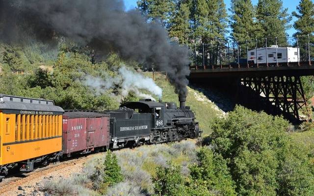 A Durango and Silverton steam train crossing a trestle with smoke rising
